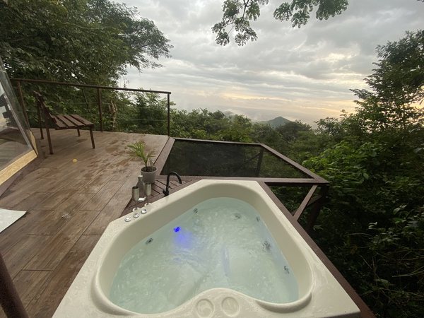 Jacuzzi en forma de corazon en deck de madera con red catamaran y vista a la selva