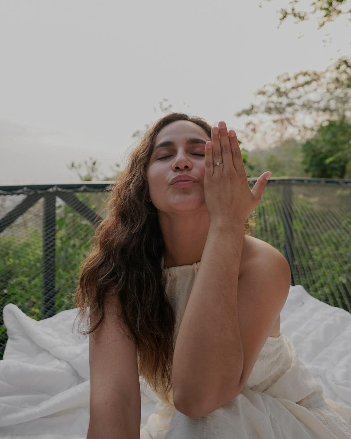 Mujer mostrando su anillo de compromiso recostada en la red catamarán rodeada de selva en Domos Mirador, Costa Rica