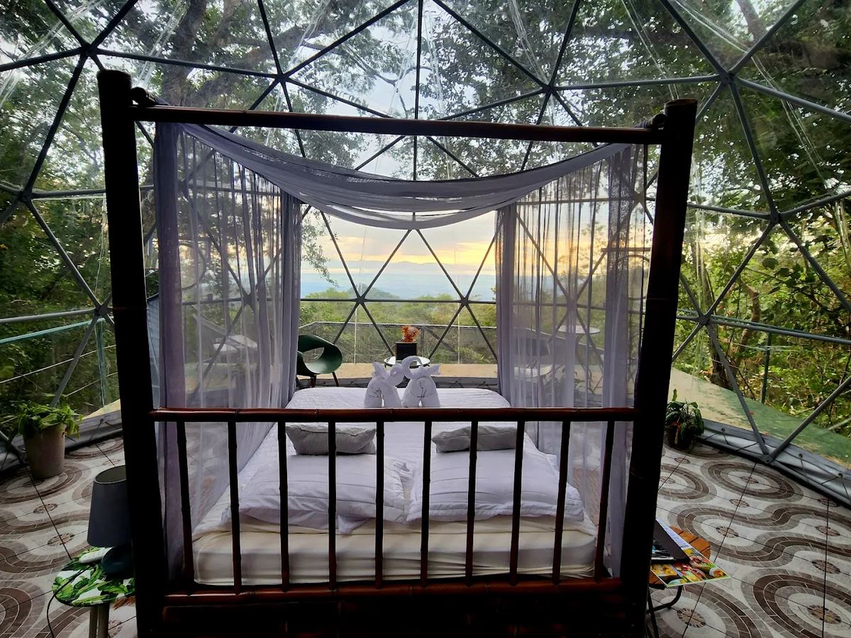Canopy bed inside the transparent dome with sunset view over the Gulf of Nicoya at Domos Mirador Costa Rica